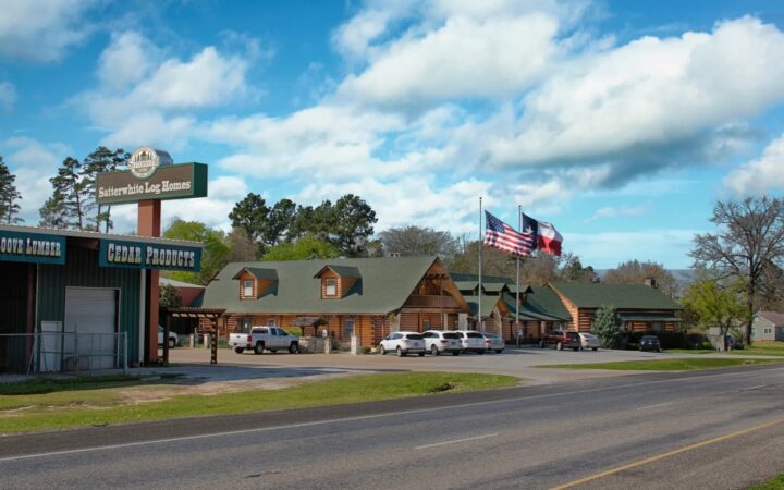 The image showcases a quaint, rustic log cabin manufactured by our company, nestled charmingly within a small town beside the road.