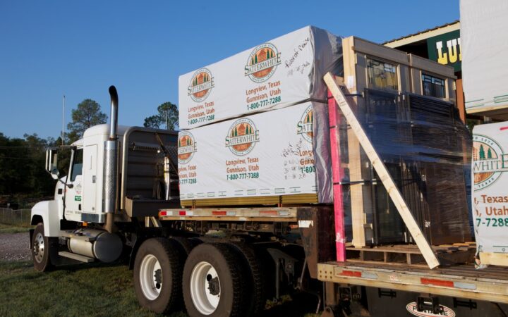 A Satterwhite Log Homes truck arrives loaded with logs.